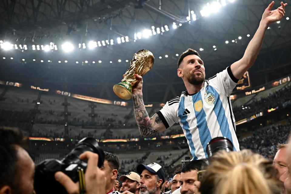 Argentina captain and forward #10 Lionel Messi (R) holds the FIFA World Cup trophy after the trophy presentation ceremony following Argentina's victory in the Qatar 2022 FIFA World Cup final between Argentina and France at Lusail Stadium in Lusail (AFP via Getty Images)