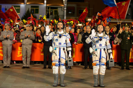 Chinese astronauts Jing Haipeng (R), Chen Dong wave before the launch of Shenzhou-11 manned spacecraft, in Jiuquan, China, October 17, 2016. China Daily/via REUTERS