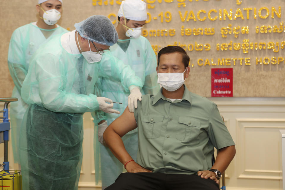 Cambodia's Lt. Gen. Hun Manet, right, a son of Prime Minister Hun Sen, receives a shot of the COVID-19 vaccine at Calmette hospital in Phnom Penh, Cambodia, Wednesday, Feb. 10, 2021. Cambodia began its inoculation campaign against the COVID-19 virus with vaccines donated from China, the country’s closest ally. (AP Photo/Heng Sinith)