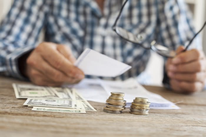 Man sitting at a table with coins and dollar bills in front of him.