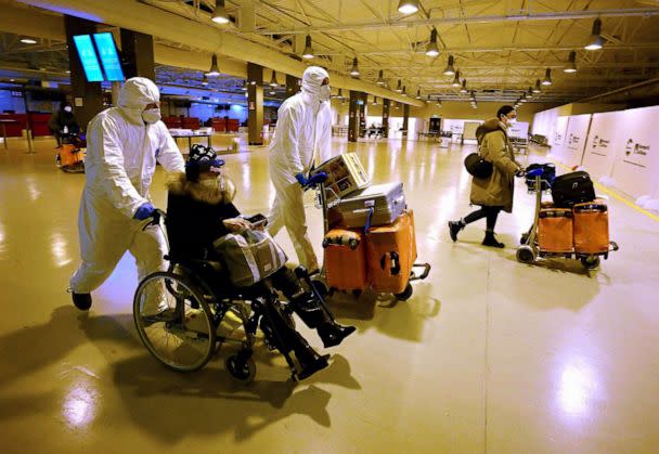 PHOTO: Workers wearing protective masks and suits help Chinese travellers leaving the arrival hall of RomeFiumicino International Airport, near Rome, Dec. 29, 2022 after being tested for the Covid-19 coronavirus. (Filippo Monteforte/AFP via Getty Images)