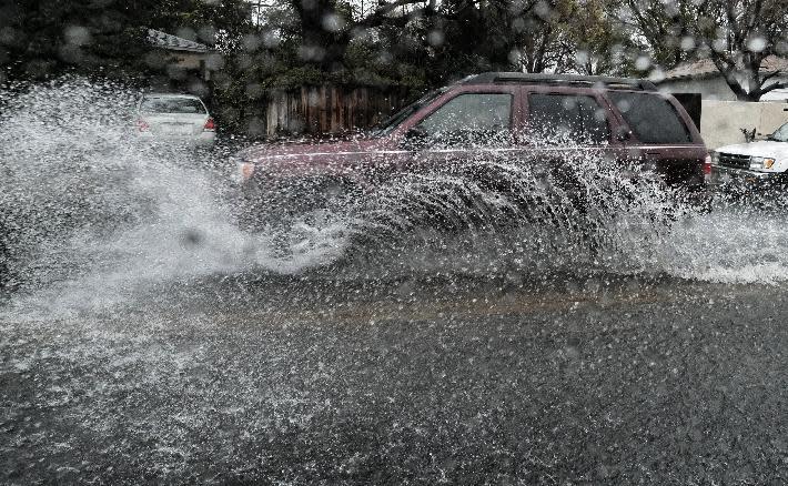 A car drives through a flooded street in Los Angeles on Sunday, Jan. 22, 2017. California residents evacuated neighborhoods below hillsides scarred by wildfires as the third, and largest, in the latest series of storms brought powerful rain Sunday and warnings about flash flooding and mudslides. (AP Photo/Richard Vogel)