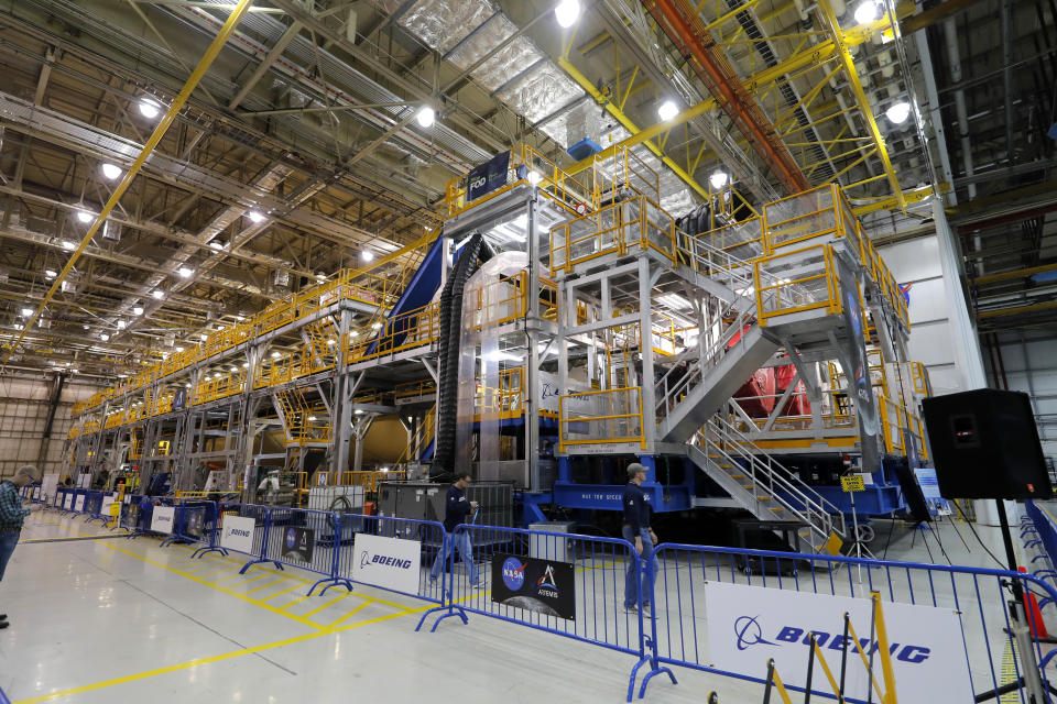 Employees walk past the core stage and four attached rocket engines (underneath scaffolding) part of NASA's Space Launch System (SLS), that will be used for the Artemis 1 mission, at the NASA Michoud Assembly Center in New Orleans, Monday, Dec. 9, 2019. (AP Photo/Gerald Herbert)