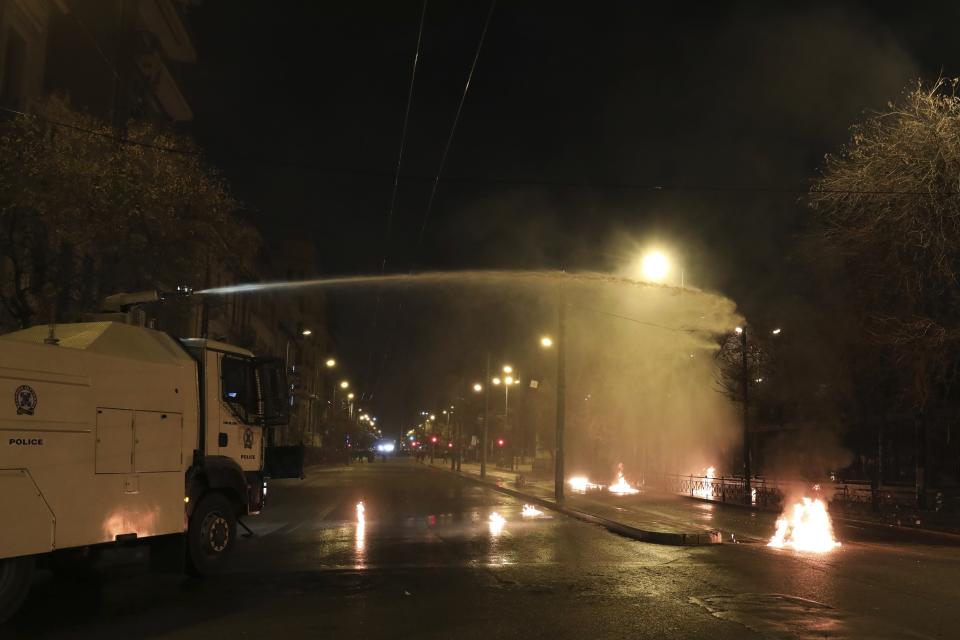 A police water canon operates against hooded youths during clashes outside the Polytechnic University in Athens, Saturday, Nov. 17, 2018. Greek police say clashes have broken out between police and anarchists in Athens and Thessaloniki on the 45th anniversary of a student uprising against Greece's then-ruling military regime. (AP Photo/Yorgos Karahalis)