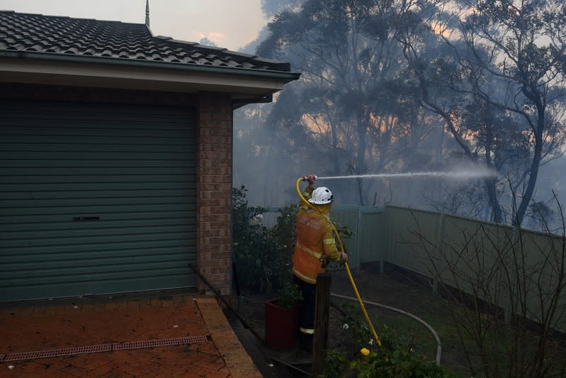 NSW Rural Fire Service personnel conducts property protection as a bushfire burns in Woodford NSW