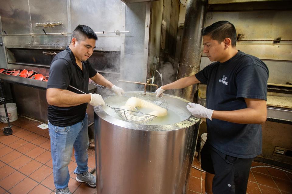 Andres Hernandez and Angel Mendez, employees of Hot Bagels, boil a giant bagel before placing it in the oven and creating a giant pizza bagel at Hot Bagels in Lakewood, NJ Monday, January 29, 2024.