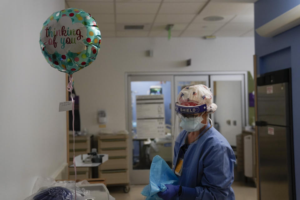 FILE - In this Jan. 7, 2021, file photo, registered nurse Anita Grohmann puts on her PPE next to a balloon delivered to a patient in a COVID-19 unit at St. Joseph Hospital in Orange, Calif. The U.S. has seen a dramatic turnaround since December and January, when hospitals were teeming with patients after holiday gatherings and pandemic fatigue caused a surge in cases and deaths. (AP Photo/Jae C. Hong, File)