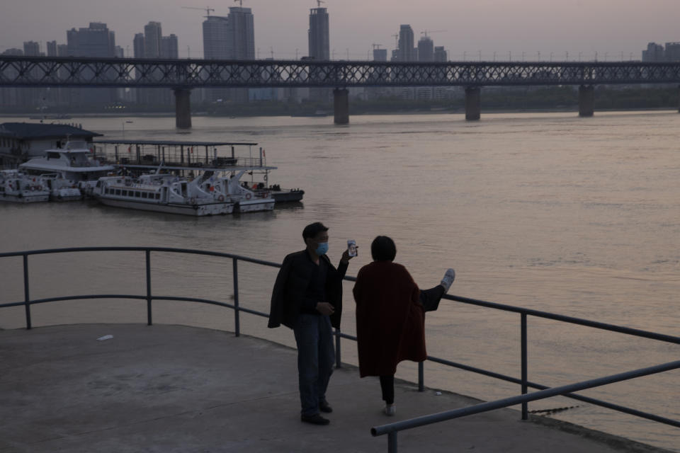 In this April 8, 2020, a man looks across the Yangtze River as the sun sets in Wuhan in central China's Hubei province. The reopening of ferry service on the Yangtze River, the heart of life in Wuhan for more than 20 centuries, was an important symbolic step in official efforts to get business and daily life in this central Chinese city of 11 million people back to normal after a 76-day quarantine ended in the city at the center of the coronavirus pandemic. (AP Photo/Ng Han Guan)