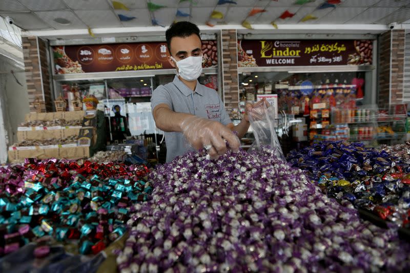 A worker packs sweets outside a shop as Palestinians prepare for the upcoming holiday of Eid al-Fitr marking the end of Ramadan, amid concerns about the spread of the coronavirus disease