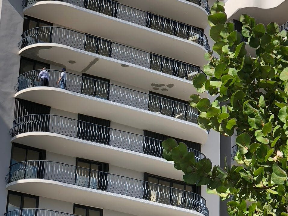 Two men inspect the bottom of a balcony.