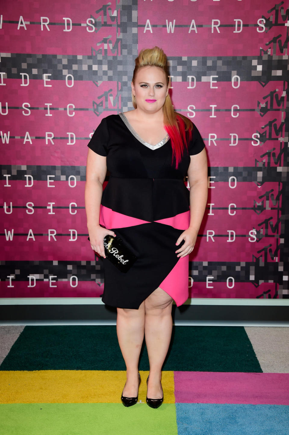 It wasn’t Rebel Wilson’s plunging black-and-pink asymmetrical Eloquii dress, black heels or graphic clutch that got everyone at the VMAs talking - it was her brand new and playful hot pink hairdo. [Photo: Getty]