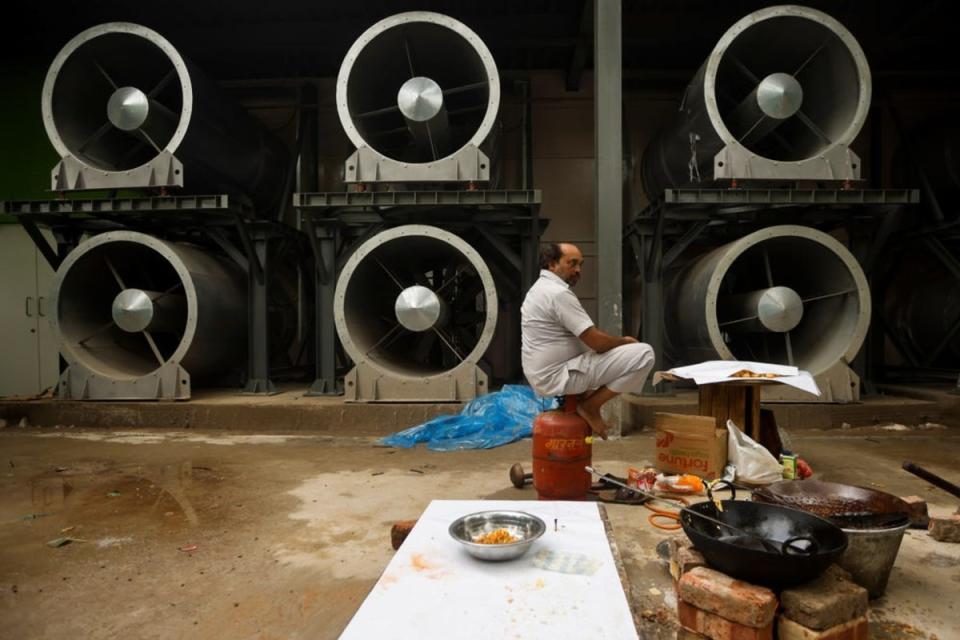 Ein Mann sitzt neben dem Smog-Turm in Neu-Delhi in Indien.