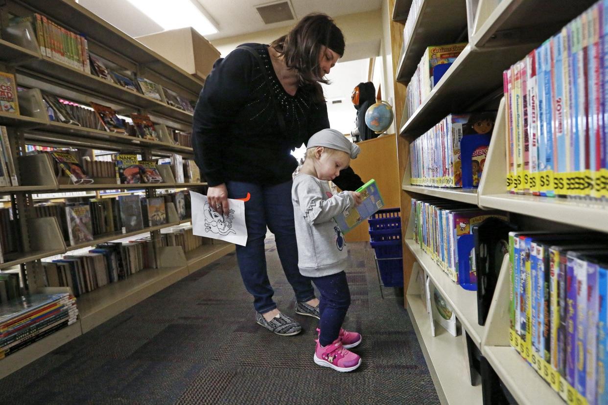 Vanessa Marich and her daughter, Lily, of Galloway, look at movies at Hurt/Battelle Memorial Library in West Jefferson on Friday, October 18, 2019. The library is asking village voters to approve a renewal levy on the Nov. 7 general election ballot that funds library operations.