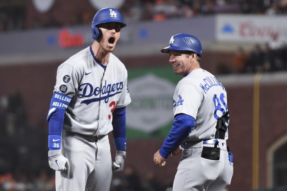 Dodgers' Cody Bellinger, left, yells to the dugout while first base coach Clayton McCullough stands next to him and smiles