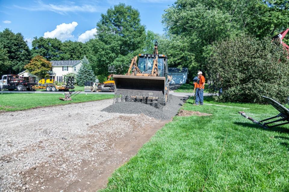 wide view of front loader grading residential path