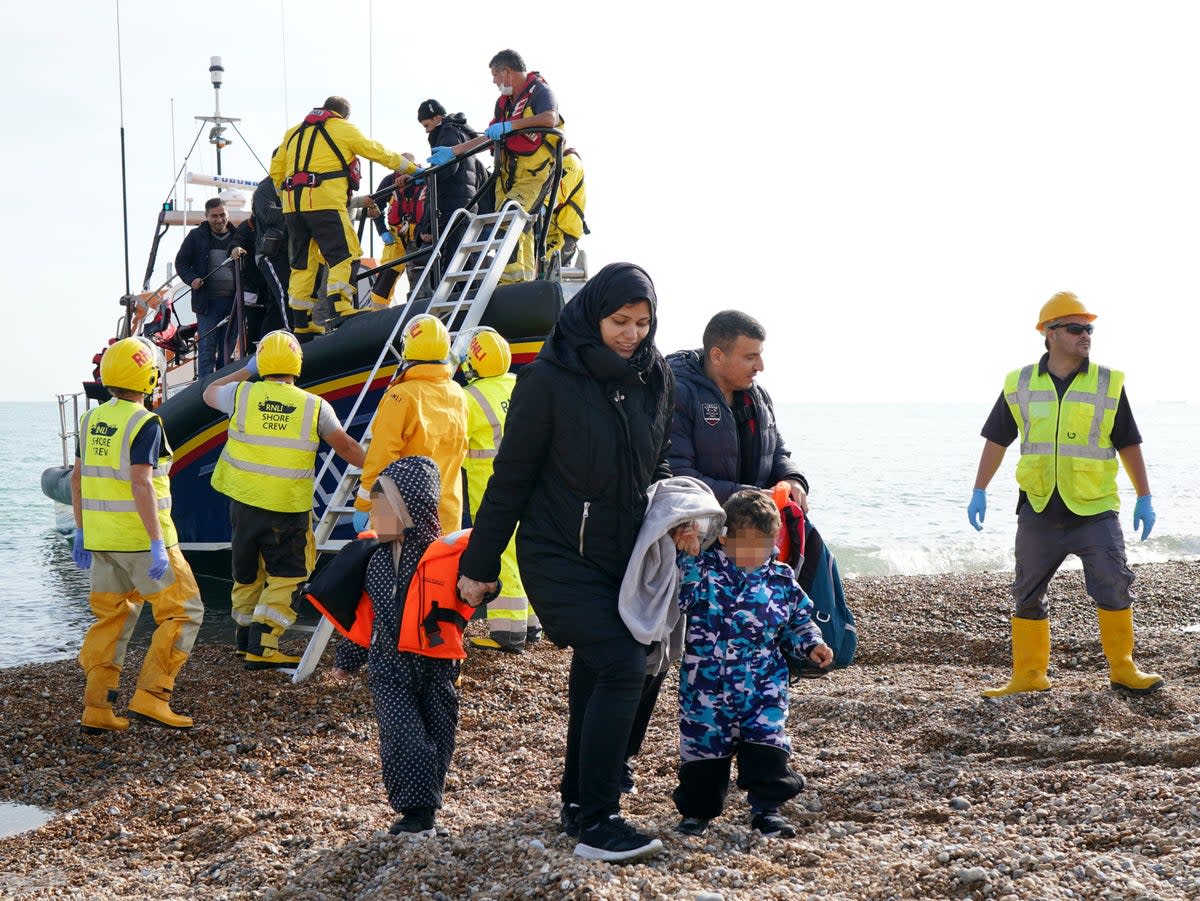 A young family are helped to shore as a group of people thought to be migrants arrive in Dungeness, Kent, after being rescued in the Channel by the RNLI following a small boat incident (Gareth Fuller/PA)