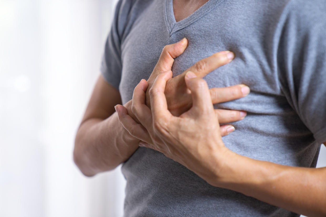 A stock image of a man with his hands over his heart.