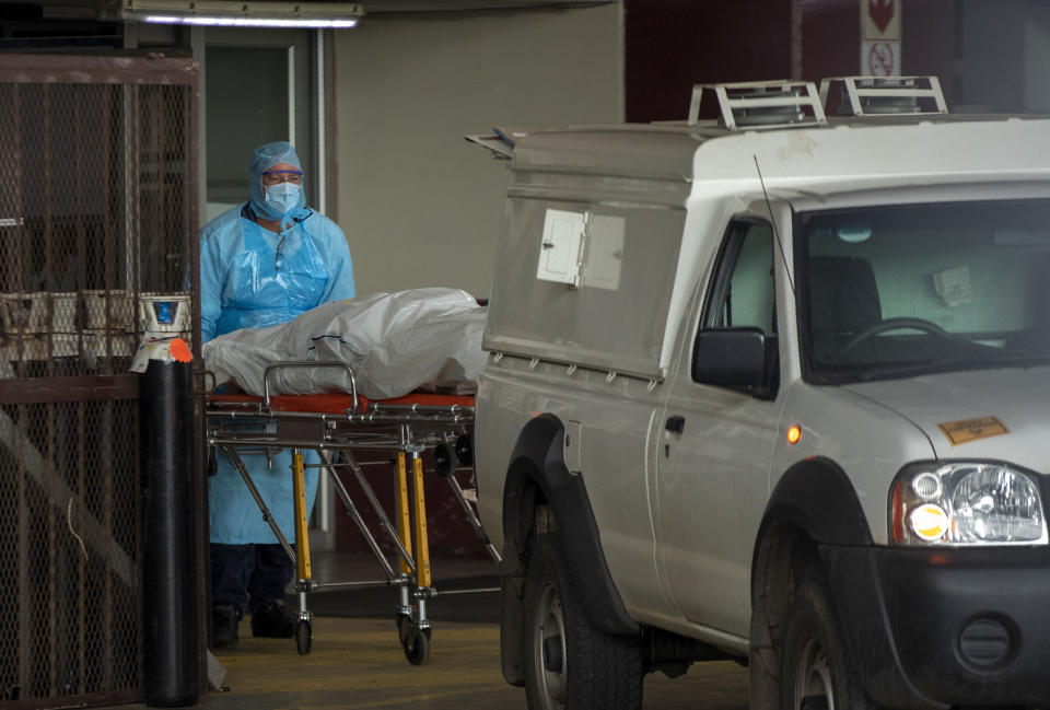 Health workers load a lifeless body into a morgue vehicle at Steve Biko Academic Hospital in Pretoria, South Africa, Monday, Jan. 11, 2021, which is battling an ever-increasing number of Covid-19 patients. (AP Photo/Themba Hadebe)