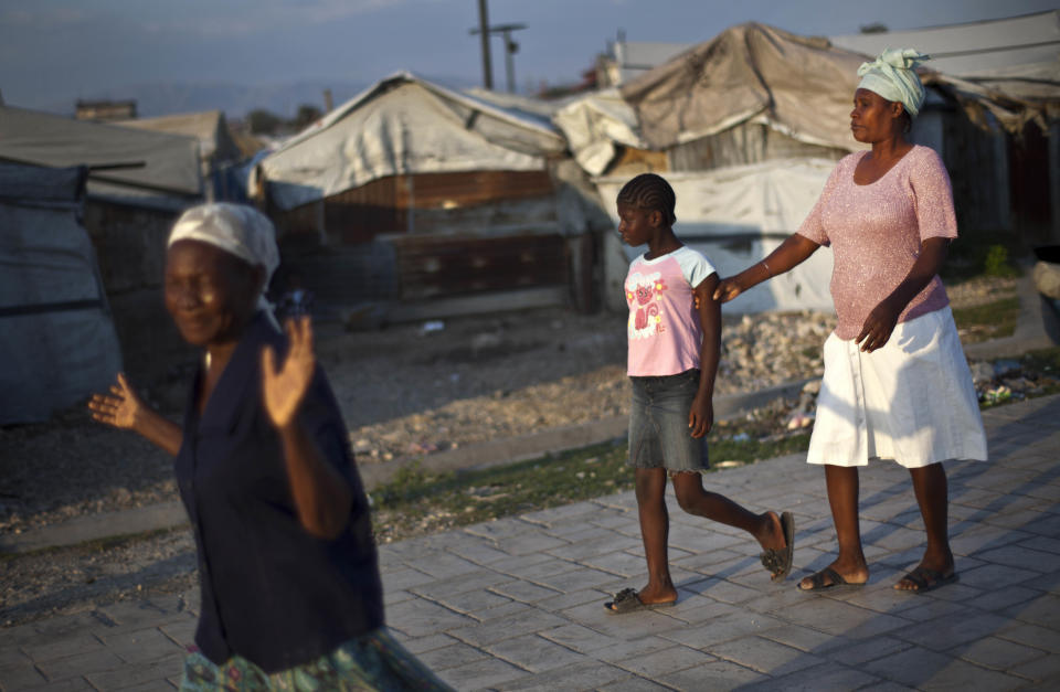 In this picture taken on Feb. 21, 2012, visually impaired Nazilia Dicque, 44, right, is led out of La Piste camp by her daughter Julienne to a nearby church in Port-au-Prince, Haiti. While more than a million people displaced by the 2010 quake ended up in post-apocalyptic-like tent cities, some of the homeless people with disabilities landed in the near-model community of La Piste, a settlement of plywood shelters along tidy gravel lanes. However, the rare respite for the estimated 500-plus people living at the camp is coming to an end as the government moves to reclaim the land. (AP Photo/Ramon Espinosa)