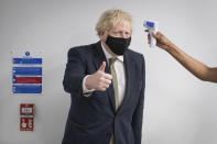 Britain's Prime Minister Boris Johnson gestures as he has his temperature checked during a visit to Chase Farm Hospital in north London, Monday Jan. 4, 2021. Johnson warned Sunday that more onerous lockdown restrictions in England are likely in the coming weeks as the country reels from a coronavirus variant that has pushed infection rates to their highest recorded levels. (Stefan Rousseau/Pool Photo via AP)