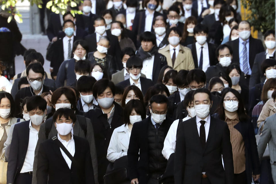 Commuters wearing face masks to protect against the spread of the coronavirus walk on a street in Tokyo, Tuesday, Nov. 17, 2020. (AP Photo/Koji Sasahara)