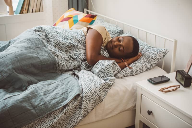 Young woman at dorm room laying in bed. It is morning and she is sleeping.