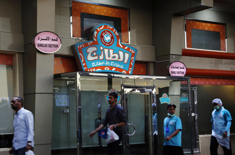 People walk in front of a restaurant with signs at top left reads, "single section," and at top right reads, "family section", in Jiddah, Saudi Arabia, Sunday, Dec. 8, 2019. Women in Saudi Arabia will no longer need to use separate entrances from single men or sit behind partitions at restaurants and cafes in the latest measure announced Sunday by the government that upends a major hallmark of the conservative restrictions that had been in place for decades. (AP Photo/Amr Nabil)