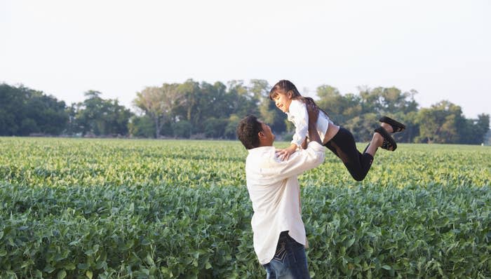 Parent lifts up child in field