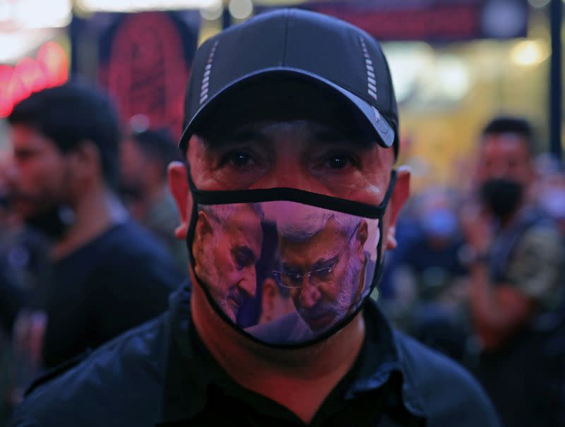 A man wears a mask with images of late Iran's Quds Force top commander Qassem Soleimani and Iraqi militia commander Abu Mahdi al-Muhandis who were killed in a U.S. airstrike, in Kerbala