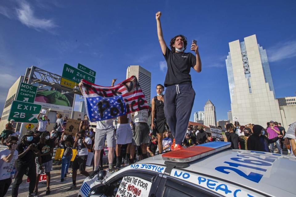 Demonstrators block I-95 and jump on a Miami Police car during a George Floyd protest in downtown Miami on Saturday, May 30, 2020.