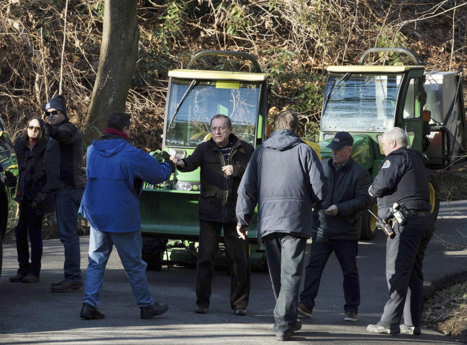 A man, center, hands a card to a federal agent as he and another attempt to drive tractors out of an estate in the village of Upper Brookville in the town of Oyster Bay, N.Y., on Long Island on Friday, Dec. 30, 2016. On Friday, the Obama administration closed this compound for Russian diplomats, in retaliation for spying and cyber-meddling in the U.S. presidential election. (AP Photo/Alexander F. Yuan)