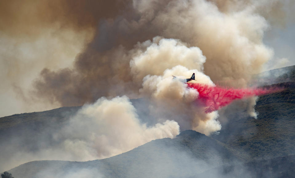 A plane drops fire retardant on a hillside in an attempt to box in flames from a wildfire during the Sand Fire in Rumsey, Calif., Sunday, June 9, 2019. (AP Photo/Josh Edelson)