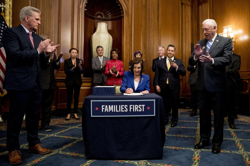 House Speaker Nancy Pelosi of Calif., accompanied by House Minority Leader Kevin McCarthy of Calif., left, House Majority Leader Steny Hoyer of Md., right, and other bipartisan legislators, signs the Coronavirus Aid, Relief, and Economic Security (CARES) Act after it passed in the House on Capitol Hill, Friday, March 27, 2020, in Washington. The $2.2 trillion package will head to head to President Donald Trump for his signature. (AP Photo/Andrew Harnik)