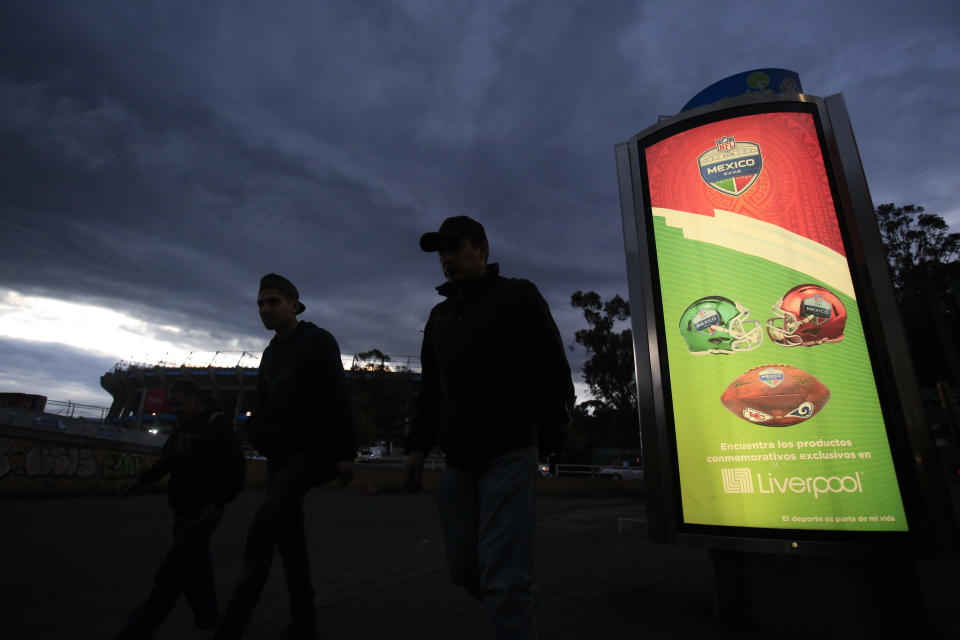 Un grupo de personas camina junto a un anuncio de una tienda departamental, alusivo a la NFL, frente al Estadio Azteca, el martes 13 de noviembre de 2018. En la jornada, la NFL mudó de esa sede a Los Ángeles un partido previsto para el próximo lunes, debido al mal estado de la cancha (AP Foto/Rebecca Blackwell)