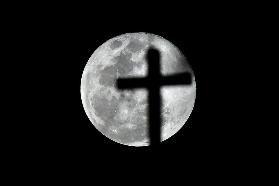 A cross is silhouetted against the full Moon in the Mexico City sky on Feb. 19.