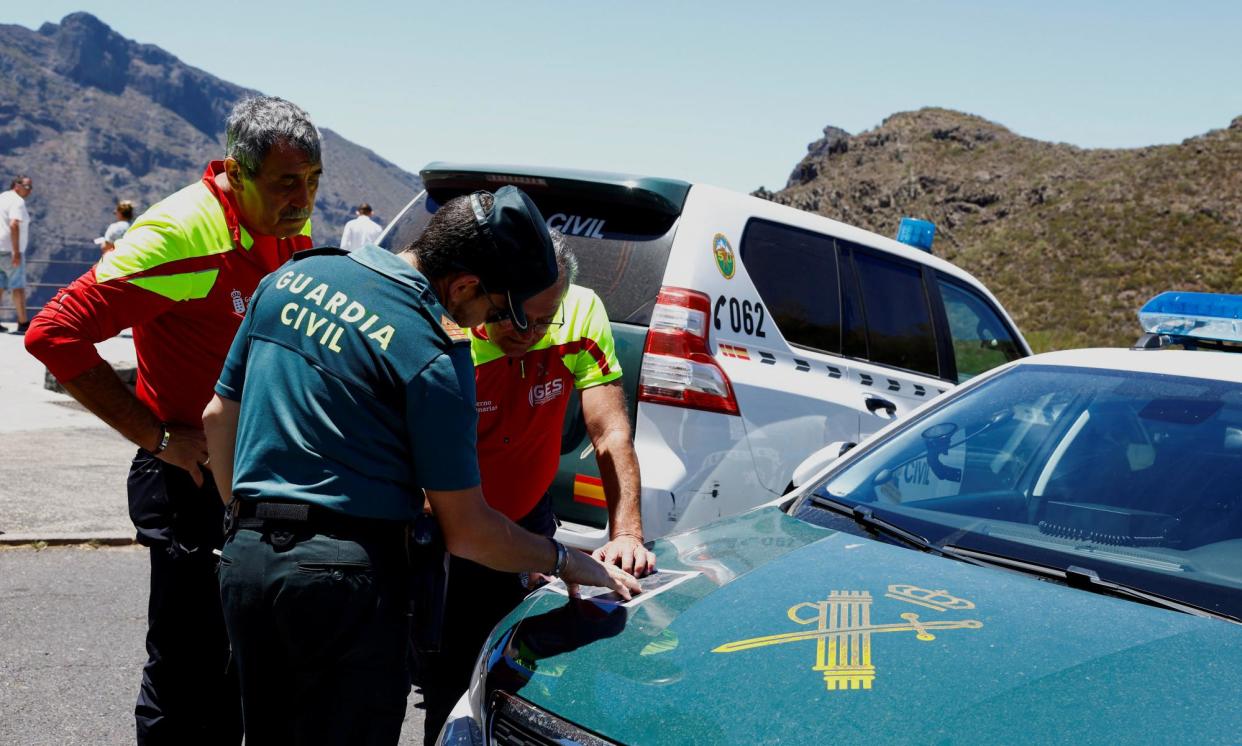 <span>A Civil Guard officer and rescuers study a map on 24 June as the search for Jay Slater in the Masca ravine, Tenerife, continues.</span><span>Photograph: Borja Suárez/Reuters</span>