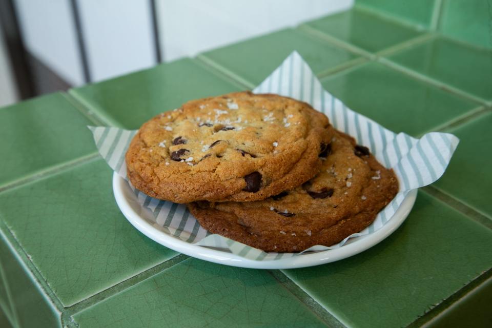 Two chocolate chip cookies rest on a plate at Central Kitchen Saturday, Aug. 26, 2023. The cookie is topped with sea salt to balance the rich dark chocolate chips.