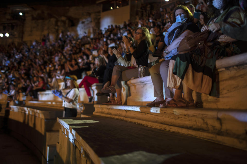 Spectators wearing protective face masks to make prevent the spread of the coronavirus clap at Odeon of Herodes Atticus in Athens, Greece, on Wednesday, July 15, 2020. The ancient theaters of Herodes Atticus in Athens and Epidaurus in the southern Peloponnese area have reopened for performances with strict seating limits and public health safety guidelines.(AP Photo/Petros Giannakouris)