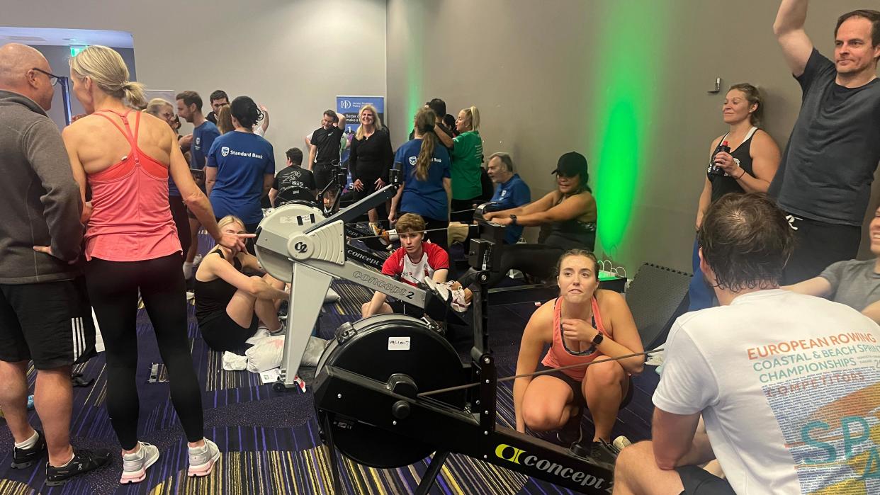 The rowathon underway with people on indoor rowing machines and supporters