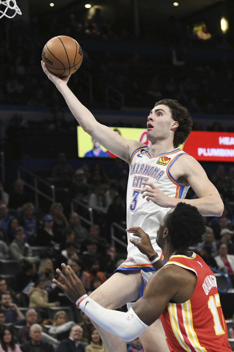 Oklahoma City Thunder guard Josh Giddey (3) goes up for a shot over Atlanta Hawks center Onyeka Okongwu (17) in the second half of an NBA basketball game, Wednesday, Jan. 25, 2023, in Oklahoma City. (AP Photo/Kyle Phillips)