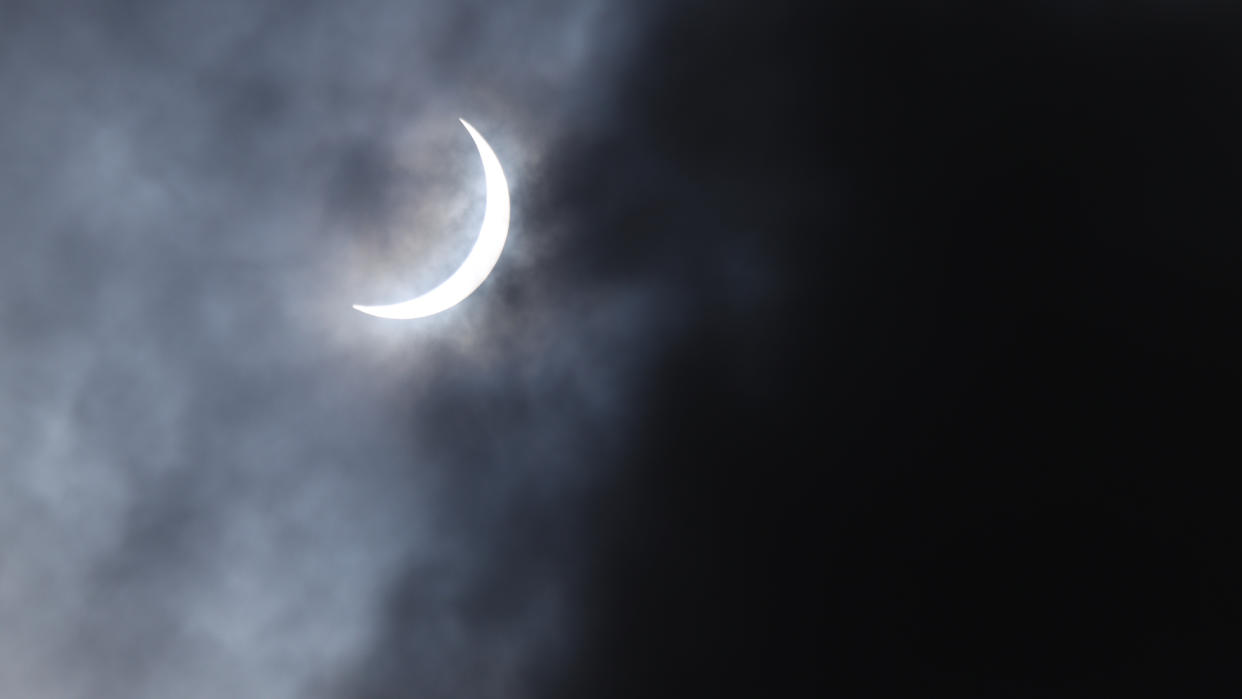  A crescent sun during a solar eclipse, shrouded in misty clouds. 