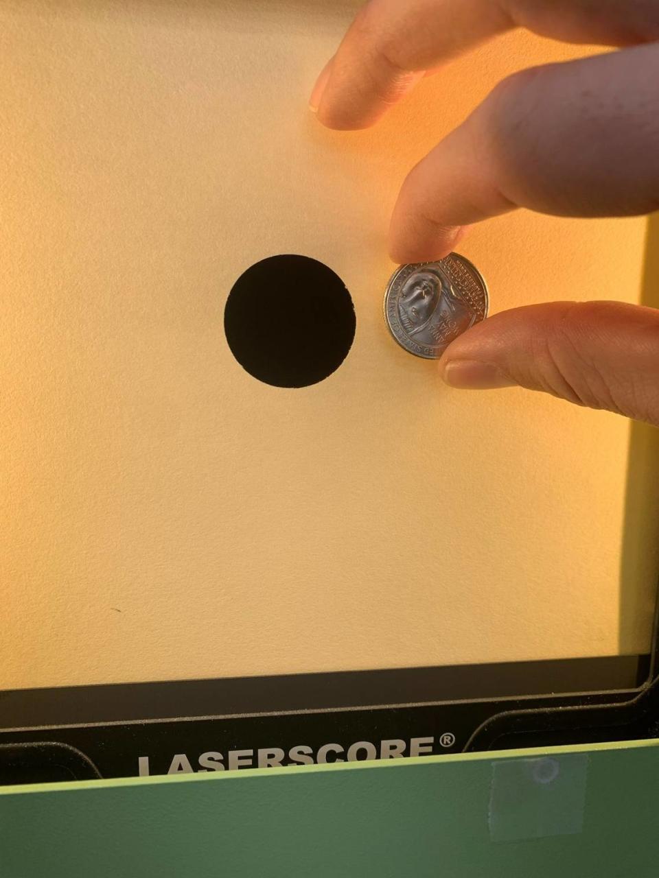 Sgt. Ivan Roe holds up a quarter to show the size of the target in the 10 meter air rifle event. The black dot shown encompasses scoring rings four through 10 in this event. Kelby Hutchison/Photo by Kelby Hutchison.