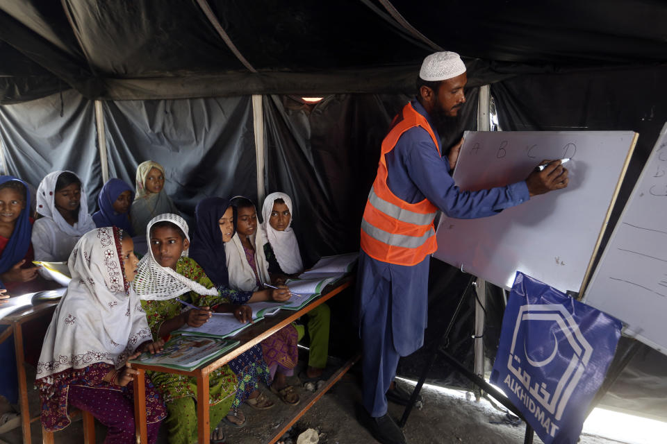 Flood affected children attend school organized by Islamic group Jamaat-e-Islami Pakistan, in Sukkur, Pakistan, Sunday, Sept. 4, 2022. Officials warned Sunday that more flooding was expected as Lake Manchar in southern Pakistan swelled from monsoon rains that began in mid-June and have killed nearly 1,300 people. (AP Photo/Fareed Khan)