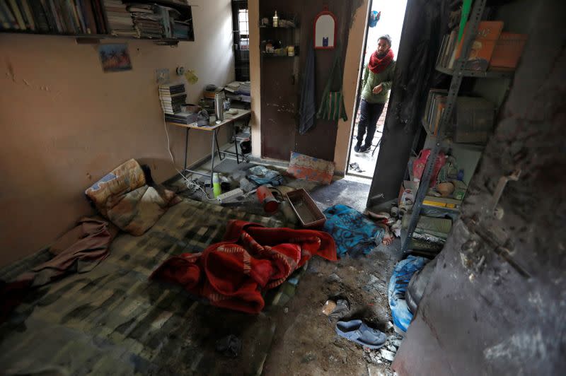 A student of Jawaharlal Nehru University looks at a damaged hostel room after it was attacked by a mob on Sunday, in New Delhi