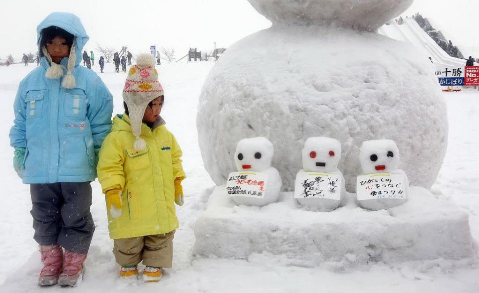 Children stand next to snowmen during the 60th Sapporo Snow Festival in Sapporo, Japan.