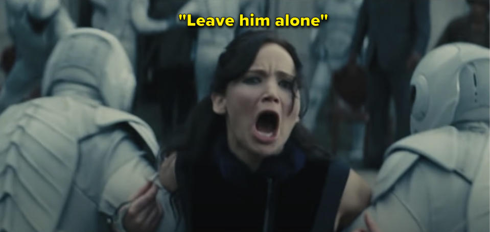 Katniss from "The Hunger Games: Catching Fire" movie screaming while being dragged away by guards with the caption "Leave him alone"