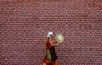 <p>A monk plays a traditional musical instrument as he walks along a street in the early morning in Colombo, Sri Lanka on May 16, 2017. (Photo: Dinuka Liyanawatte/Reuters) </p>