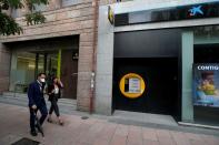 People walk past branches of Bankia and Caixabank in Madrid