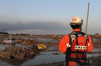 A Japanese rescuer looks at a land devastated by the tsunami in Sendai. Japan raced to avert a meltdown of two reactors at a quake-hit nuclear plant Monday as the death toll from the disaster on the ravaged northeast coast was forecast to exceed 10,000