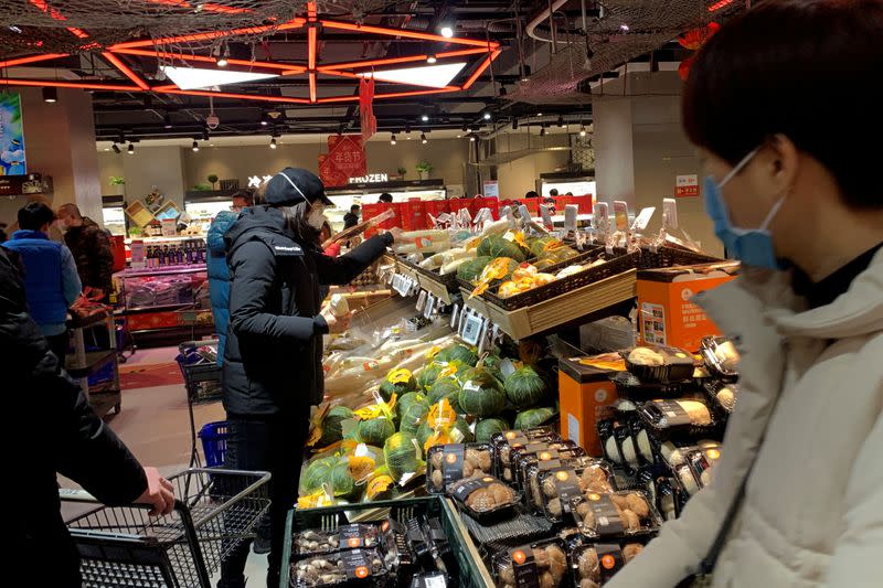 Customers wearing masks shop at the Alibaba's Hema Fresh chain store, following the coronavirus outbreak, in Beijing